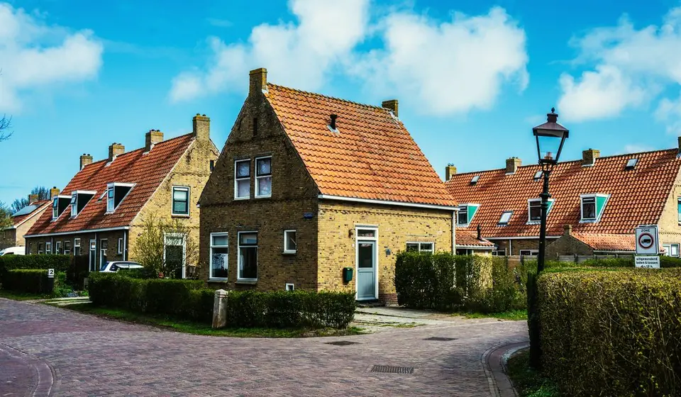 Rij Nederlandse baksteenwoningen met oranje dakpannen